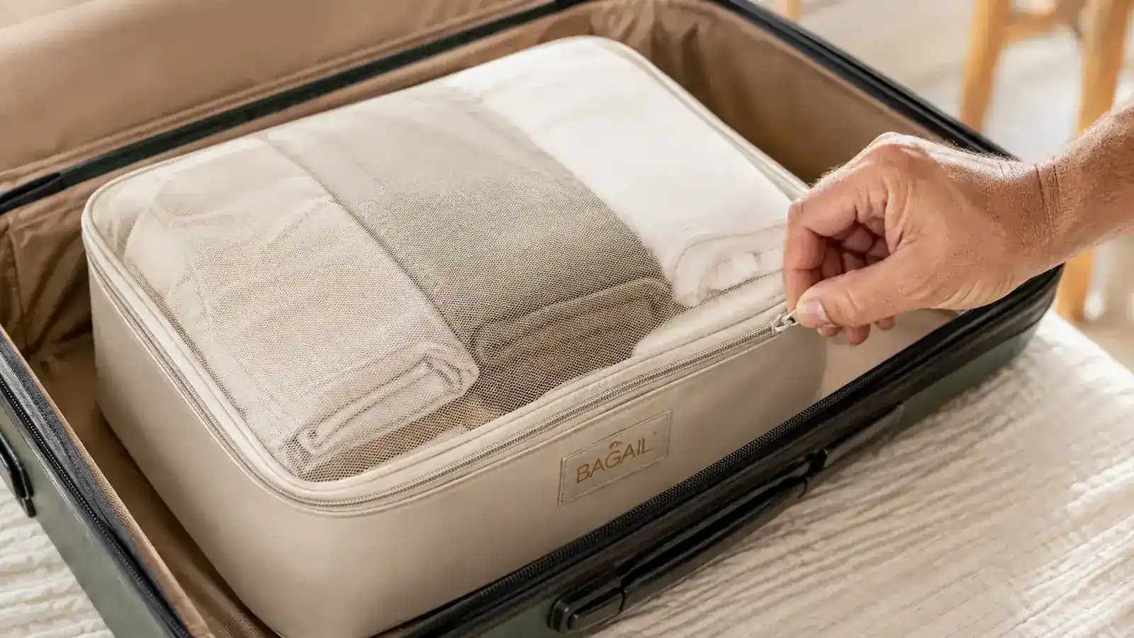 Hand zipping a medium BAGAIL packing cube full of folded shirts