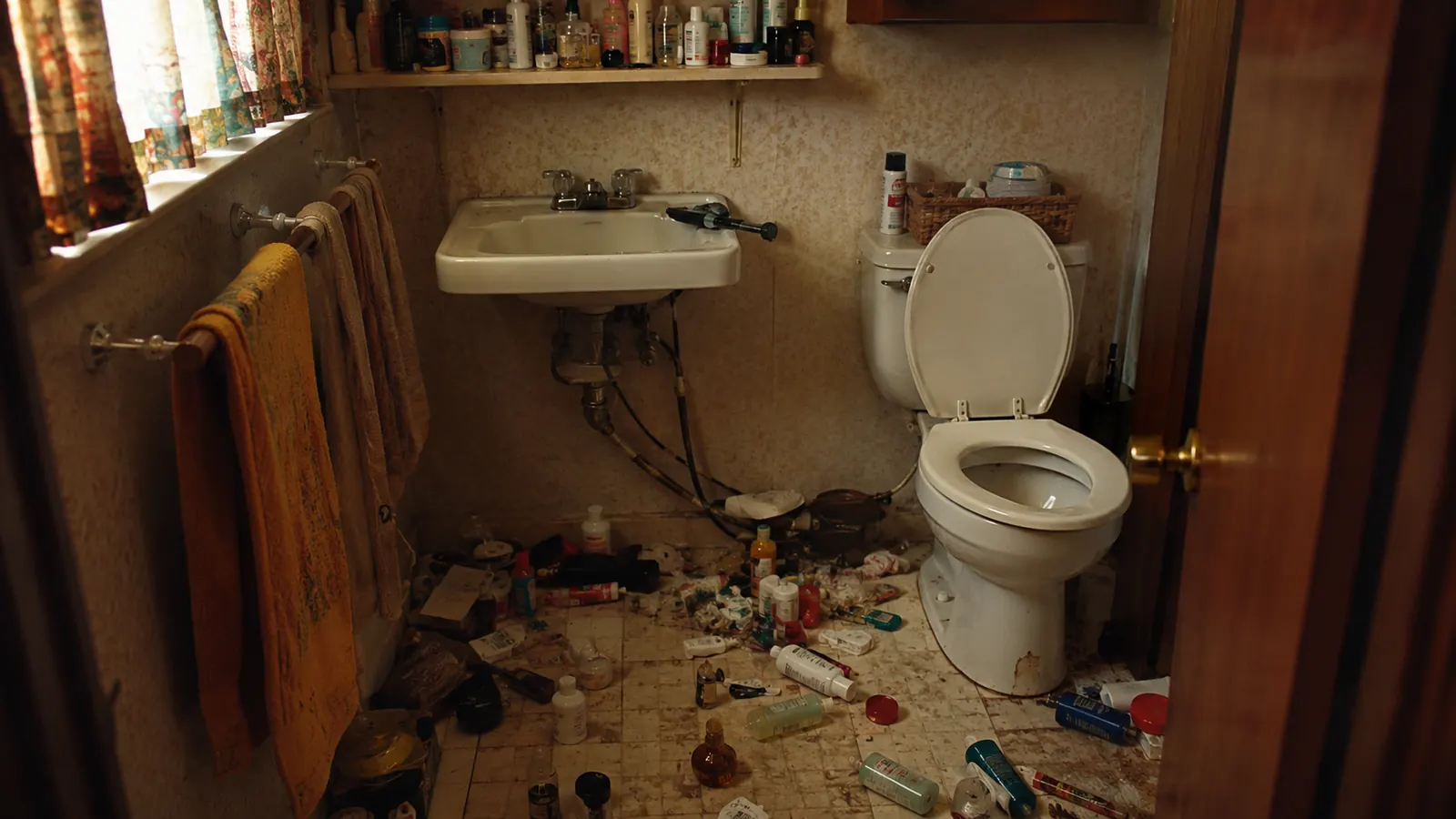 Cracked aftershave bottle and scattered toiletries on a worn cabin bathroom floor